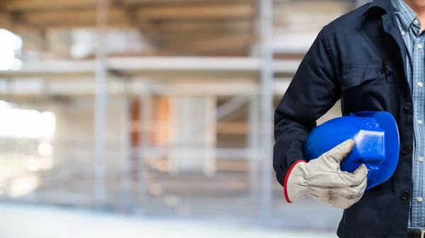 Chantier de construction extérieur avec contremaître en tenue de sécurité consultant une tablette numérique